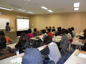 スクリーンで説明する講師と20人の受講生